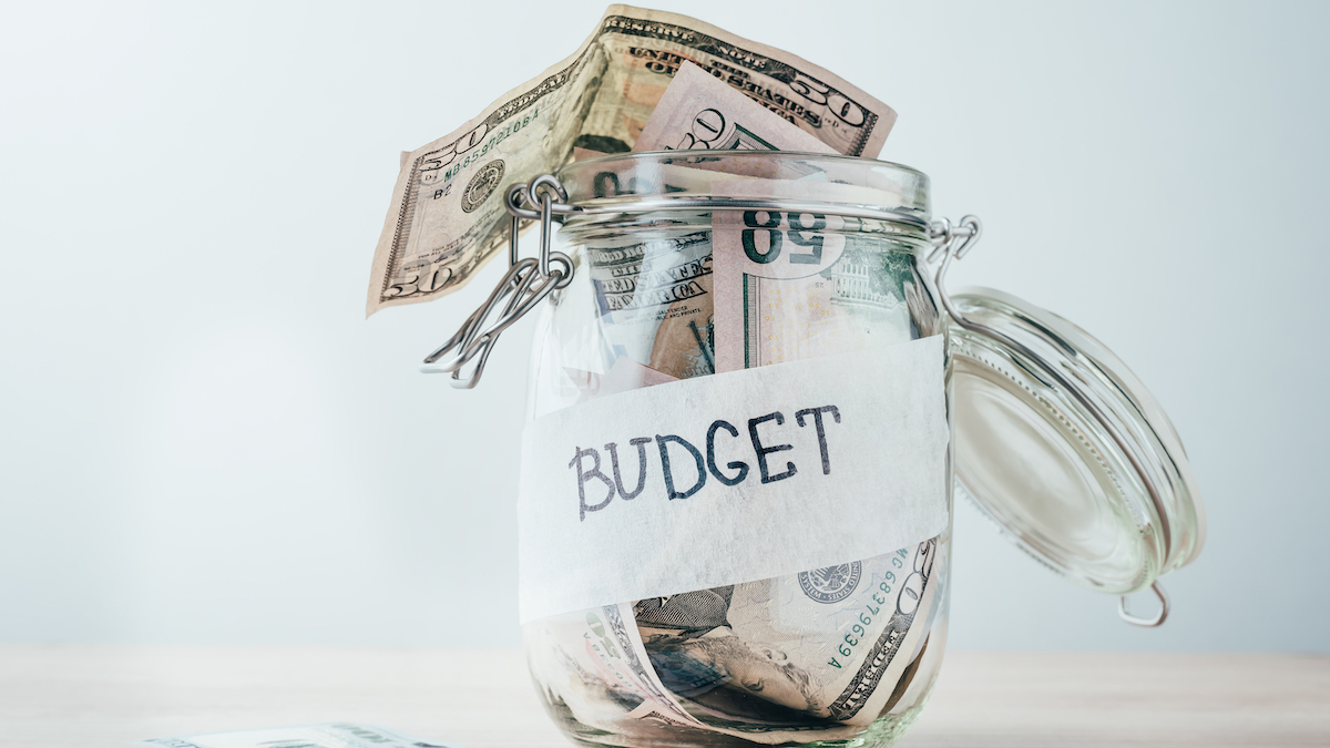 A jar labeled "budget" filled with cash.